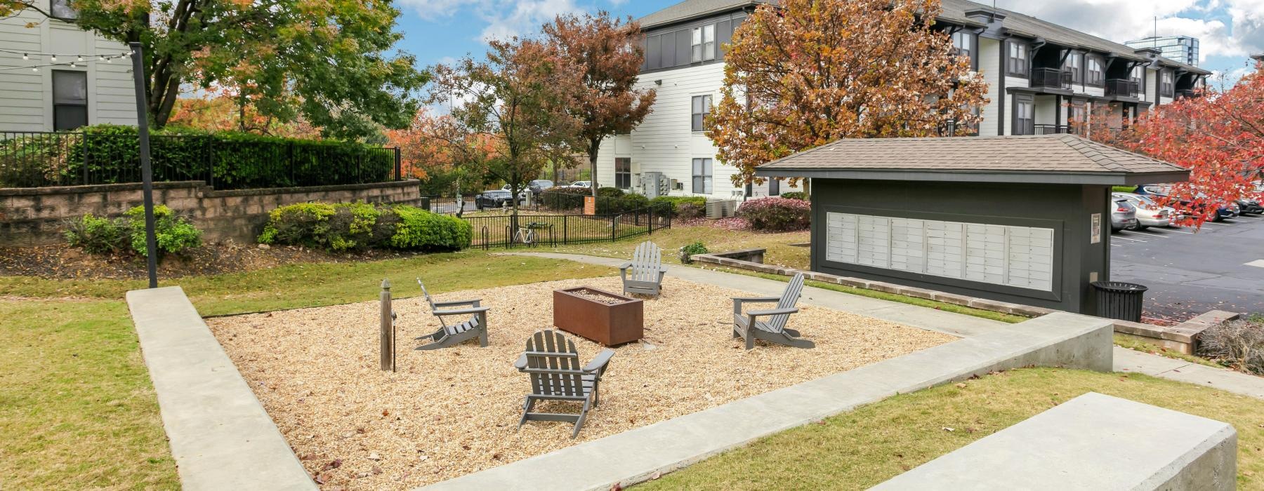 sand filled square with fire pit and lawn chairs adjacent to mail boxes